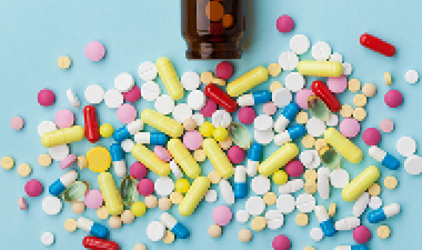 brown bottle with a variety of pills and capsules spread out in front