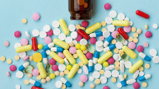 brown bottle with a variety of pills and capsules spread out in front