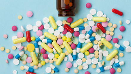 brown bottle with a variety of pills and capsules spread out in front